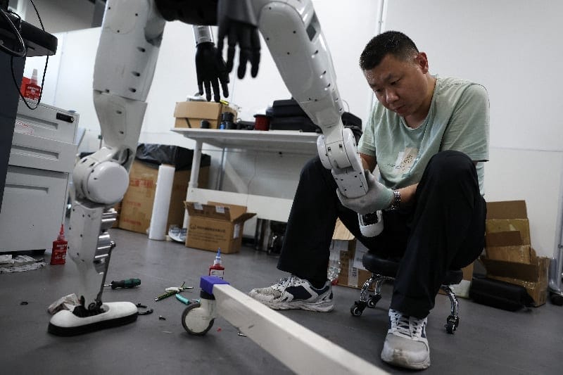 An engineer works on the leg of a Tiangong Omni humanoid robot in the research and testing area of the Beijing Humanoid Robot Innovation Center, also known as X-Humanoid, in Beijing, China, September 4, 2026. REUTERS/Tingshu Wang
