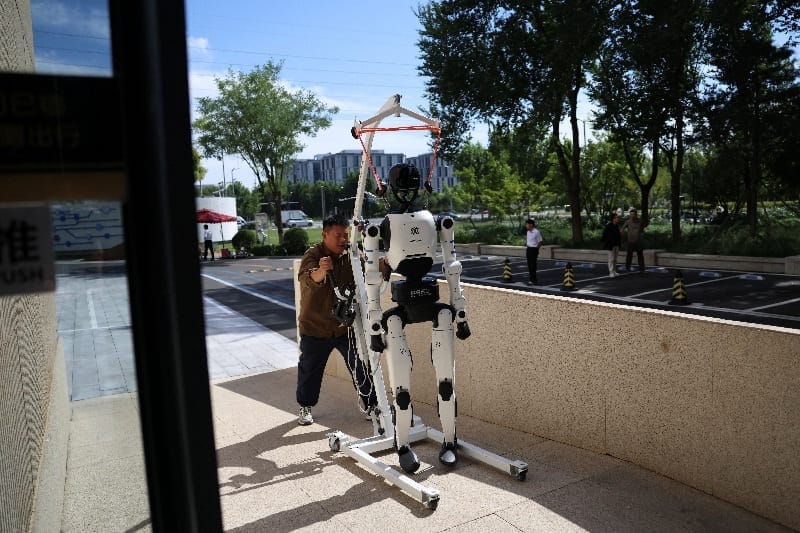 An employee moves a Tiangong humanoid robot with a mobile crane at the Beijing Humanoid Robot Innovation Center, also known as X-Humanoid, in the Yizhuang development area of Beijing, China, September 4, 2026. REUTERS/Tingshu Wang