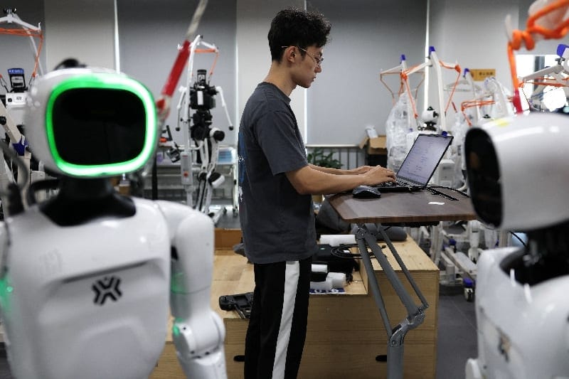An engineer works among Tiangong Omni and Tiangong Ultra humanoid robots in the research and testing area of the Beijing Humanoid Robot Innovation Center, also known as X-Humanoid, in Beijing, China, September 4, 2026. REUTERS/Tingshu Wang