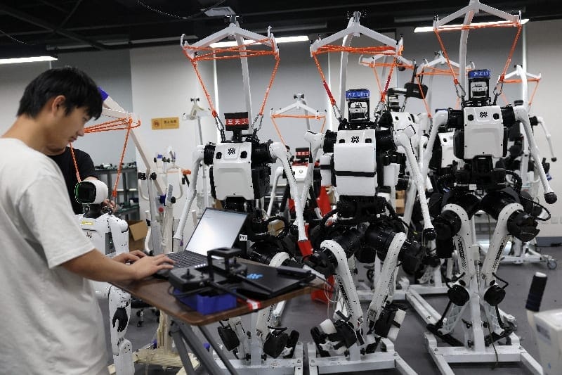 An engineer works next to Tiangong Ultra humanoid robots in the research and testing area of the Beijing Humanoid Robot Innovation Center, also known as X-Humanoid, in Beijing, China, September 4, 2026. REUTERS/Tingshu Wang