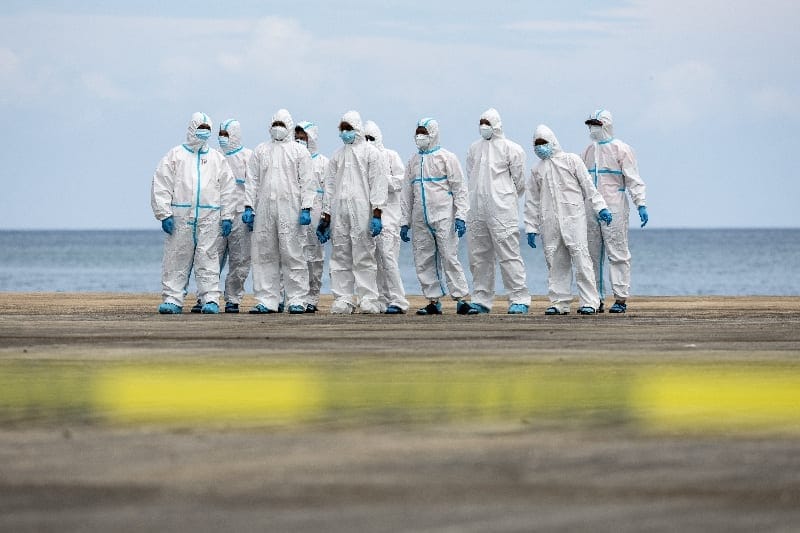 Members of the Philippine Coast Guard wearing personal protective equipment stand at the Port of Borac after delivering body bags containing the recovered remains of victims of a fire aboard the MV June Aster ferry off the coast of Palawan, in Coron,