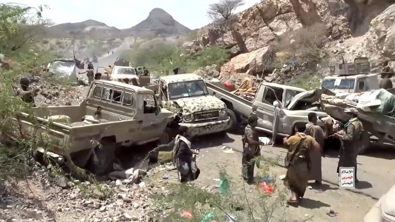 Fighters gather near damaged military vehicles in the aftermath of what a Houthi-owned TV network says are strikes on pro-government forces at an unknown location in Yemen, in this still image taken from video released September 12, 2026. Al-Masirah
