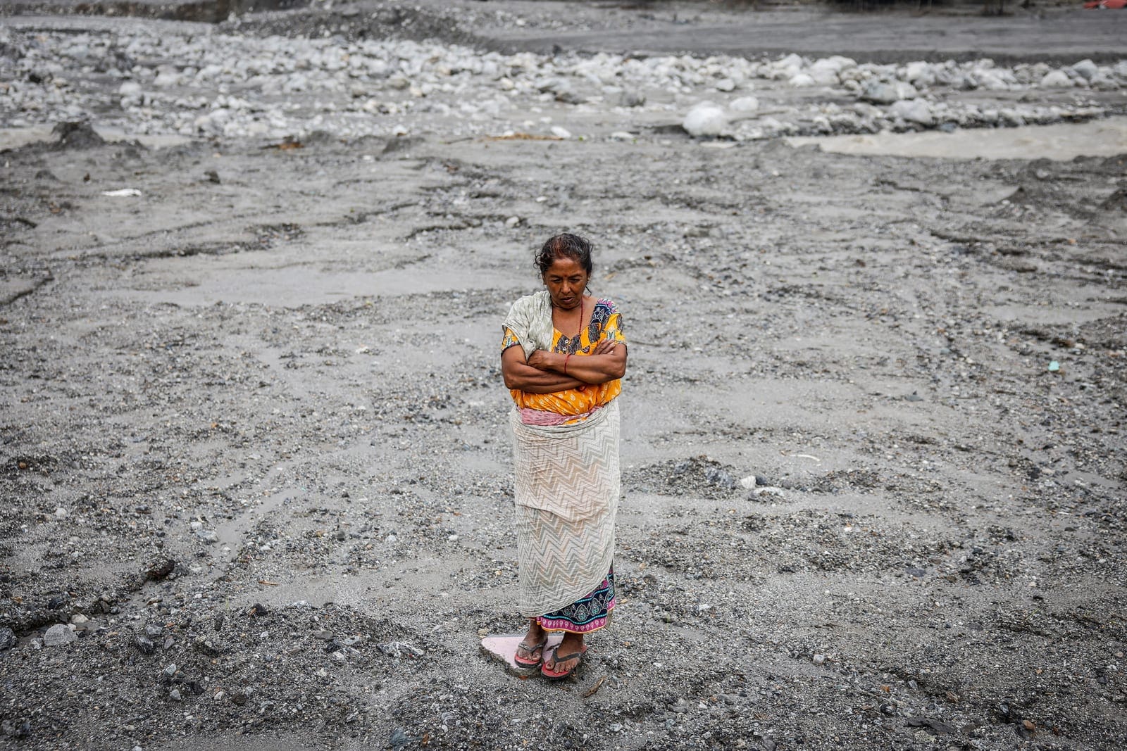 Shanti Dangol, 61, displaced by recent flash floods and mudslides, poses for a photograph on the sludge that buried her home in Betrawati, Nuwakot district, Nepal, September 9, 2026. Shanti described Betrawati as a once-thriving town that catered to 