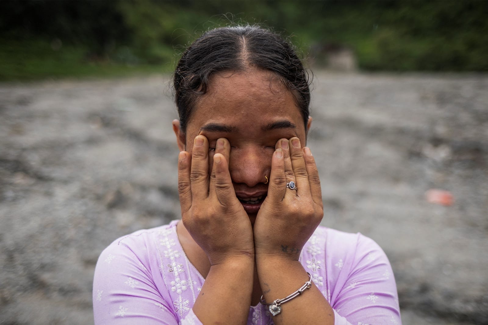 Anusa Thapa Magar, 23, displaced by recent flash floods and mudslides, cries as she poses for a photograph on the sludge that buried her home in Betrawati, Nuwakot district, Nepal, September 9, 2026. Magar returned from working in the Maldives after 