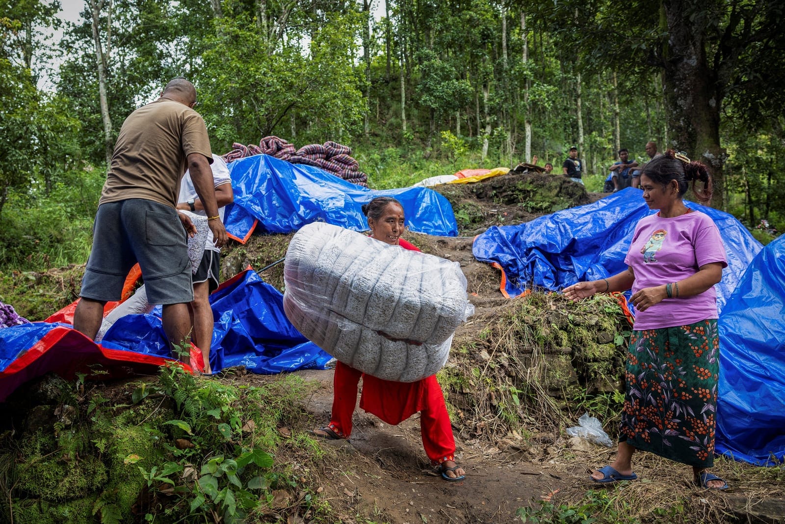 Chary Thapa Magar, displaced by flash floods and mudslides, carries a sack of aid supplies at a temporary shelter on a hill in Betrawati, Nuwakot district, Nepal, September 9, 2026. Each day, scores of survivors sheltering in clusters of tents on a h