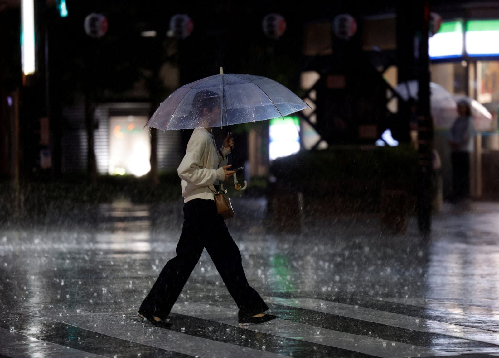 A woman crosses a street in heavy rain as a result of Typhoon Dujuan in Tokyo, Japan, September 21, 2026. REUTERS/Kim Kyung-Hoon