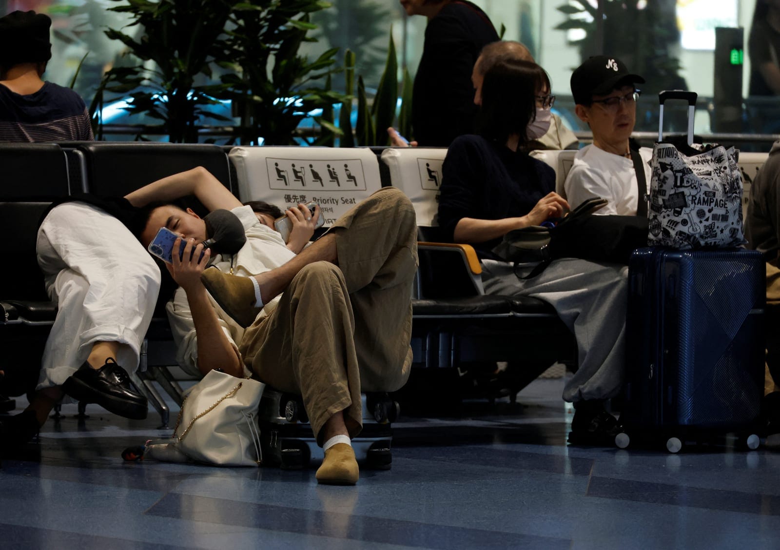 Passengers rest at Haneda Airport as many flights are delayed and cancelled due to Typhoon Dujuan, in Tokyo, Japan, September 21, 2026. REUTERS/Kim Kyung-Hoon