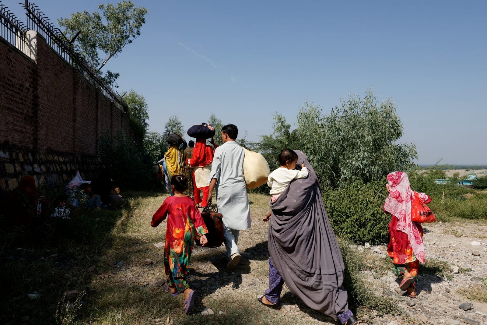 A family walks to their village after police closed the Grand Trunk Road ahead of a planned march by former Pakistani Prime Minister Imran Khan's party, PTI, from Peshawar to Islamabad, Pakistan, September 25, 2026. REUTERS/Staff