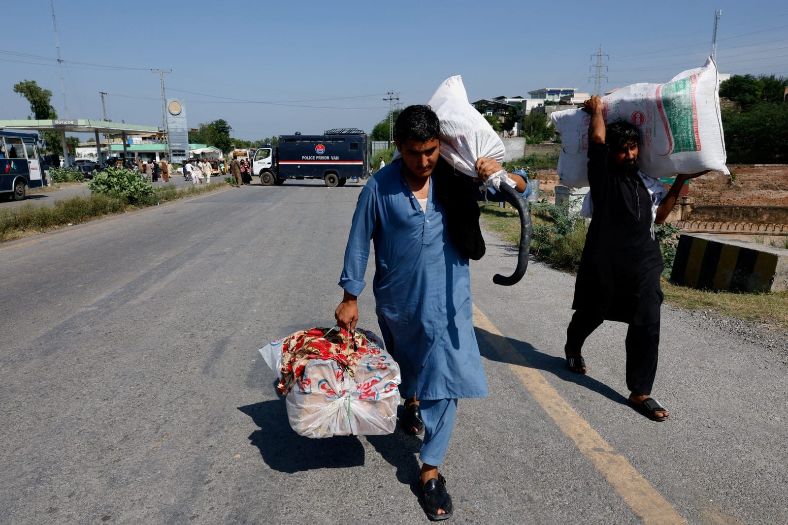 Men carry belongings as they walk to their village after police closed the Grand Trunk Road ahead of a planned march by former Pakistani Prime Minister Imran Khan's party, PTI, from Peshawar to Islamabad, Pakistan, September 25, 2026. REUTERS/Staff