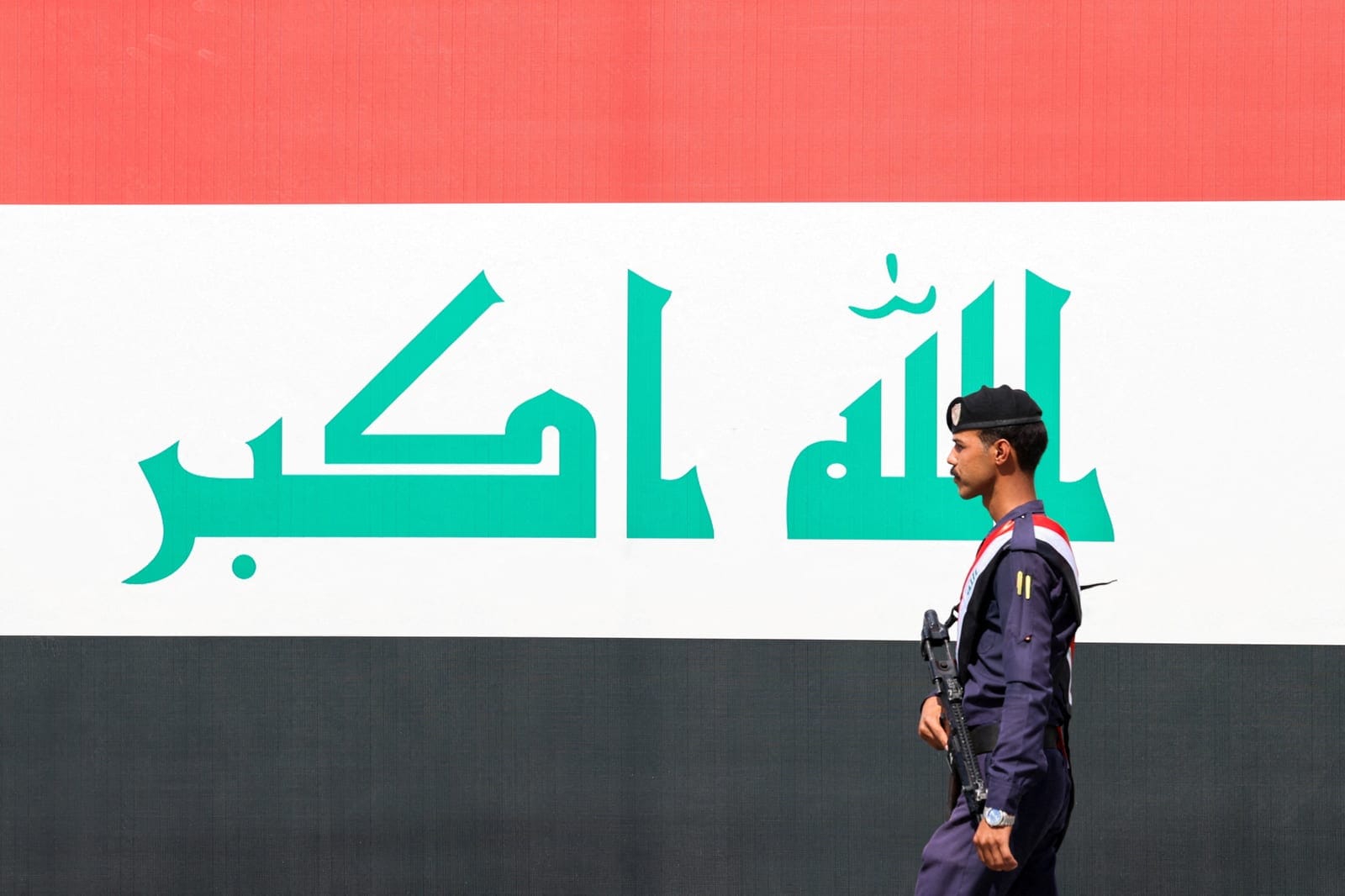 A member of the Iraqi security forces walks past a display of an Iraqi flag as they celebrate the withdrawal of US-led coalition forces from Iraq, ending a military presence that began after the 2003 US-led invasion, in Baghdad, Iraq, September 30, 2