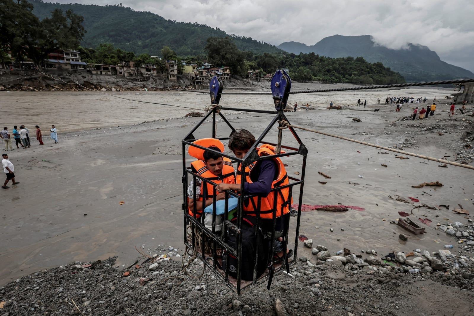 People hold onto a cage on a makeshift zip line as they cross the Trishuli River from Devighat following deadly flash floods that damaged bridges and temporarily stranded residents, in Nuwakot district, Nepal, September 5, 2026. REUTERS/Navesh Chitra