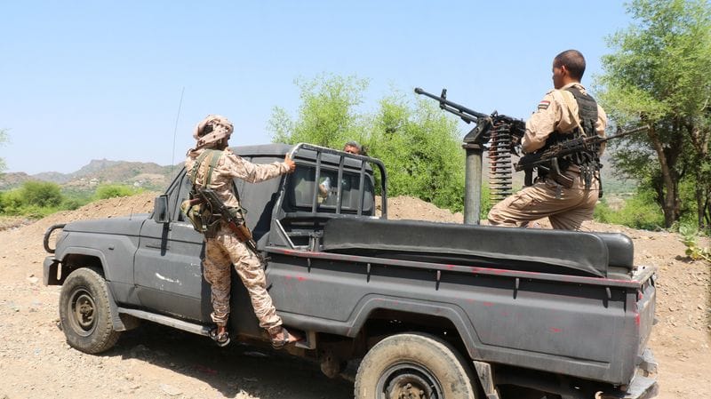 Government soldiers ride military pick-up vehicle on road leading to frontline in Taiz