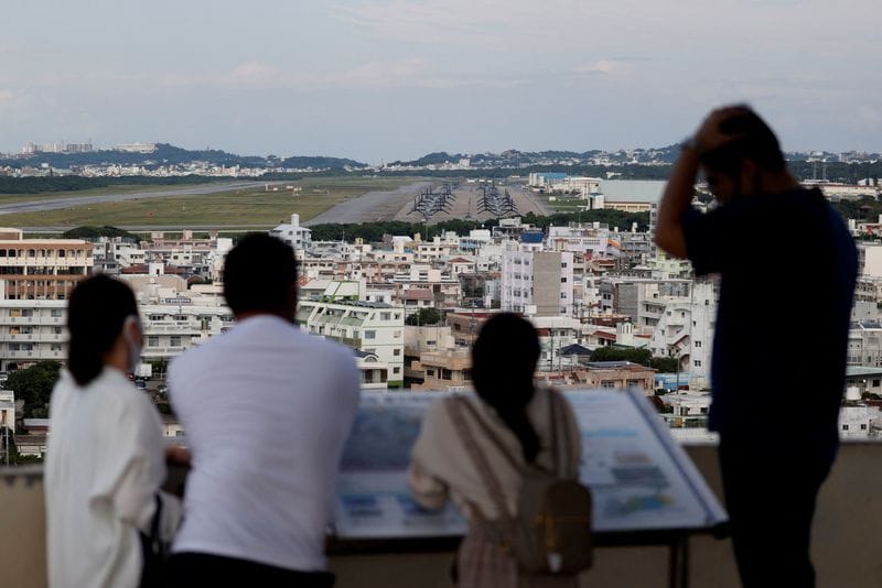 FILE PHOTO: People look at the U.S. Marine Corps' Futenma Air Station in Ginowan on the southern island of Okinawa