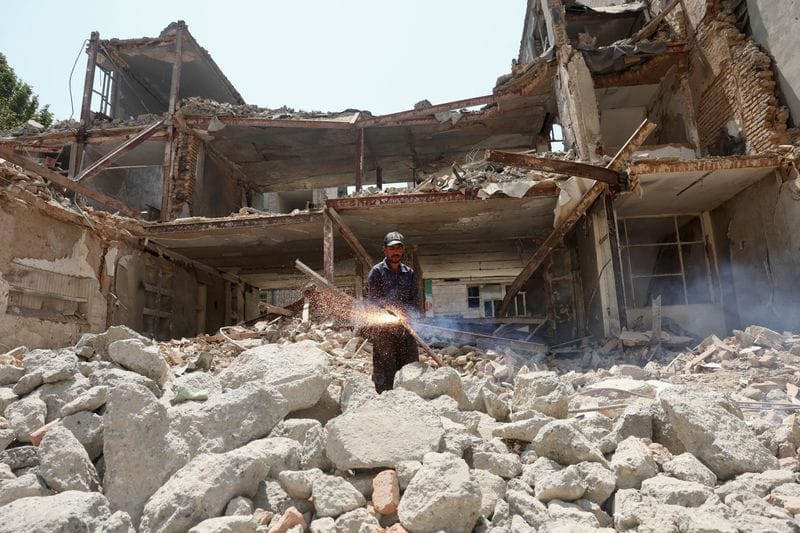 A man works near a building, which was damaged in a U.S. and Israeli strike in March, in Tehran