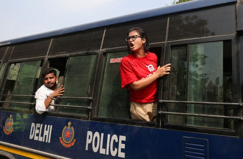 Neha Bora, National President of the All India Students' Association (AISA), shouts from a police vehicle after being detained during a protest organised by the Cockroach Janta Party (CJP)