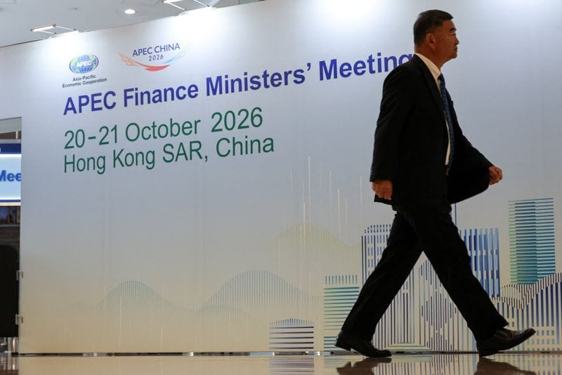 A man walks past a sign for the APEC Finance Ministers' Meeting in Hong Kong
