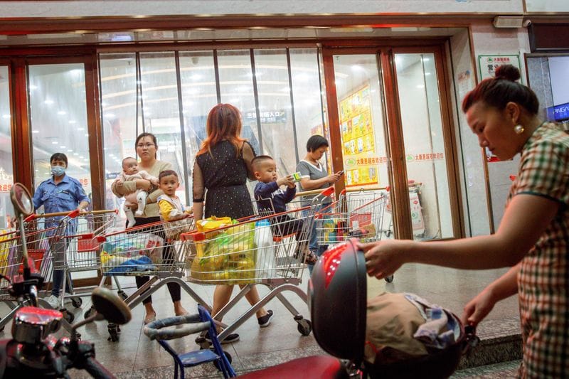 A woman holds a baby outside a supermarket in Qinzhou