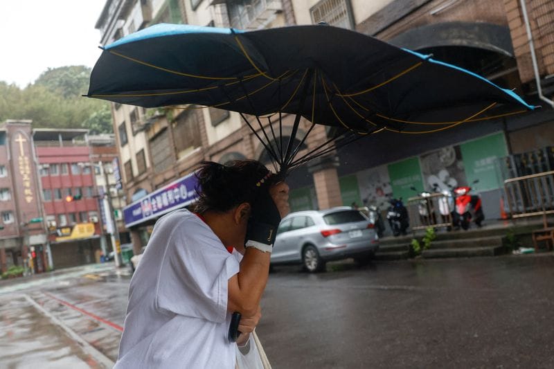 A pedestrian holds a damaged umbrella as Typhoon Champi approaches Taiwan, in Keelung