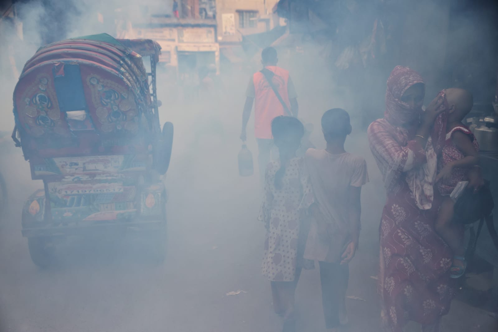 A woman covers her child's face as a man fumigates a road as a preventive measure against mosquito-borne diseases, particularly dengue, in Dhaka, Bangladesh, October 1, 2026. REUTERS/Mohammad Ponir Hossain