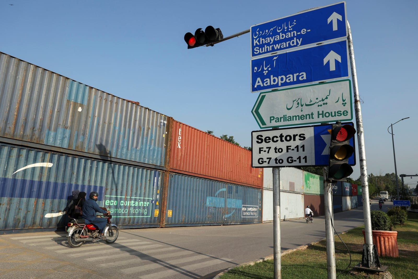 A man on motorbike rides past shipping containers used to block the area in the background, ahead of a planned march by former Pakistani Prime Minister Imran Khan's party Pakistan Tehreek-e-Insaf (PTI), in Islamabad, Pakistan, September 30, 2026. REU
