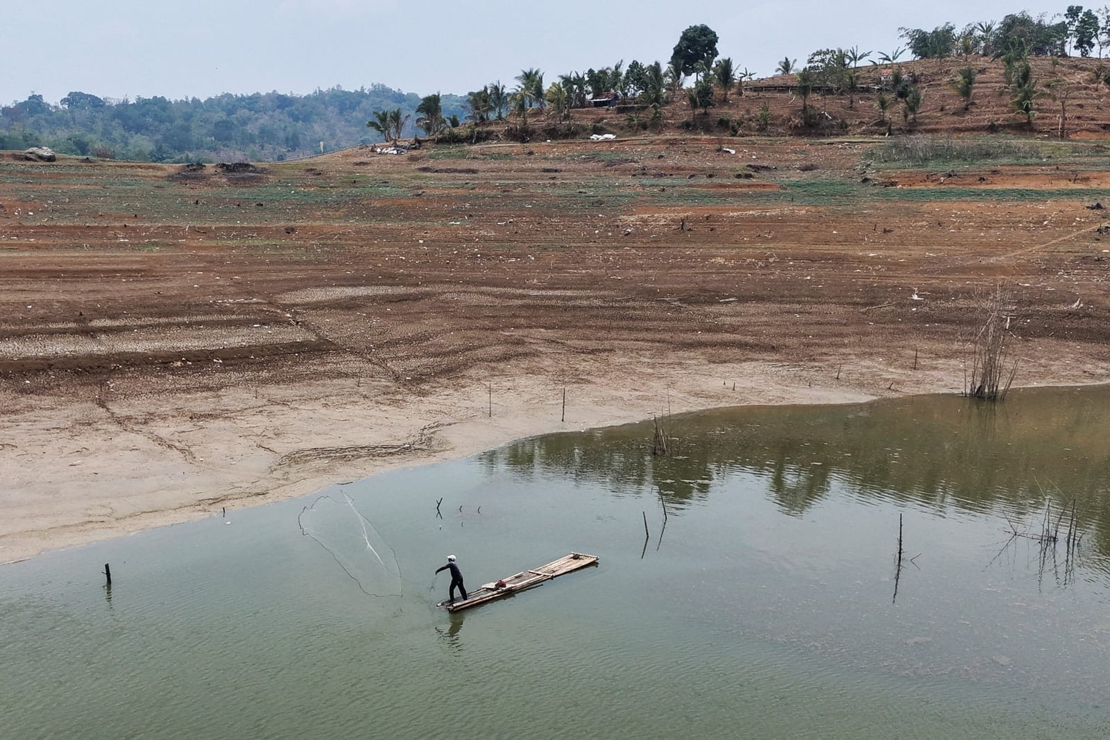 A drone view shows a fisherman casting his net at Jatigede Reservoir as water levels recede amid drought during the dry season in Sumedang Regency, West Java province, Indonesia, October 1, 2026. REUTERS/Claudio Pramana