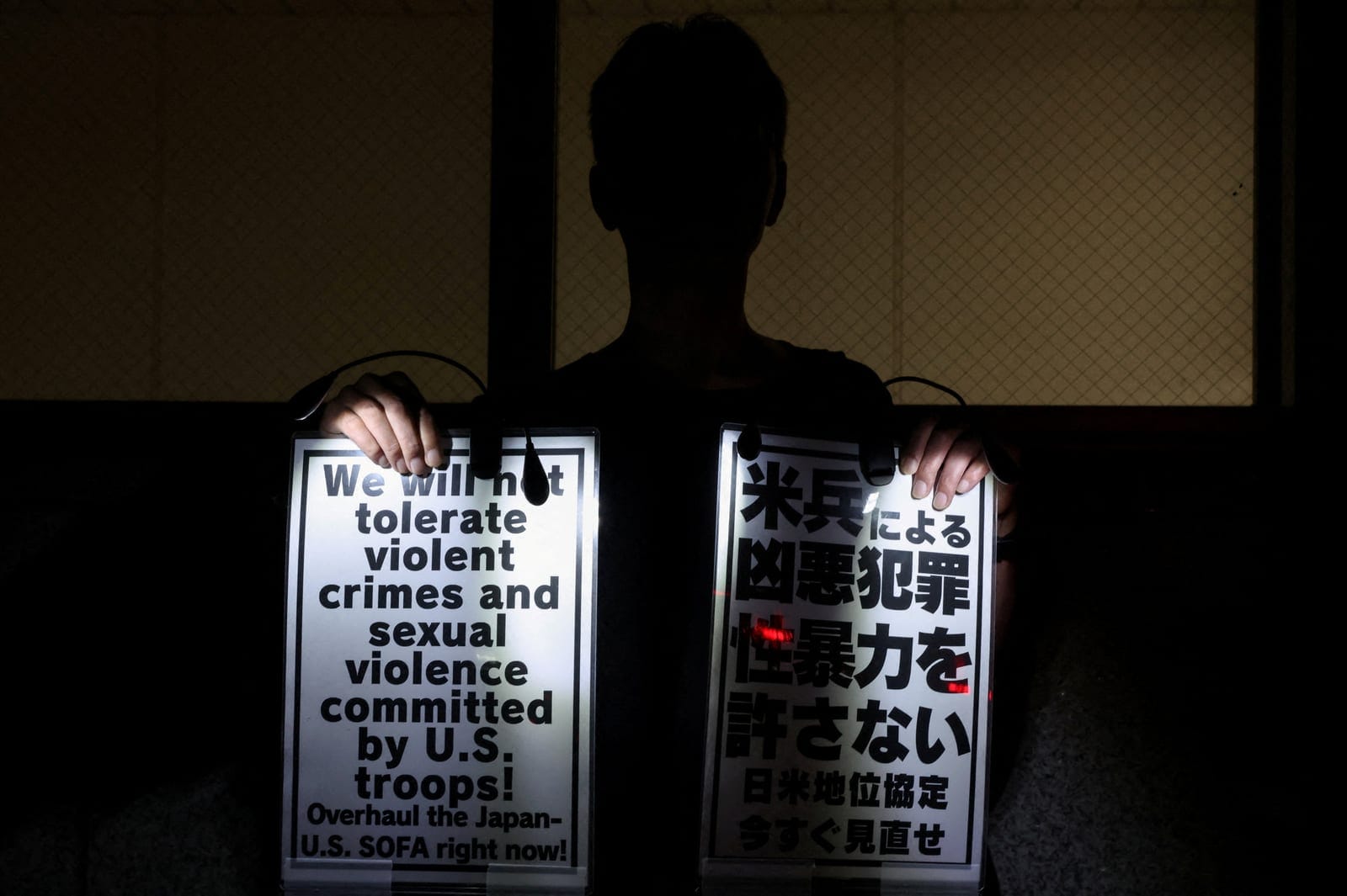 A demonstrator holds placards during a protest outside the Prime Minister's office following the killing of a Japanese woman in Okinawa, for which a US Marine is a suspect, in Tokyo, Japan, October 5, 2026. REUTERS/Kim Kyung-Hoon TPX IMAGES OF THE DA