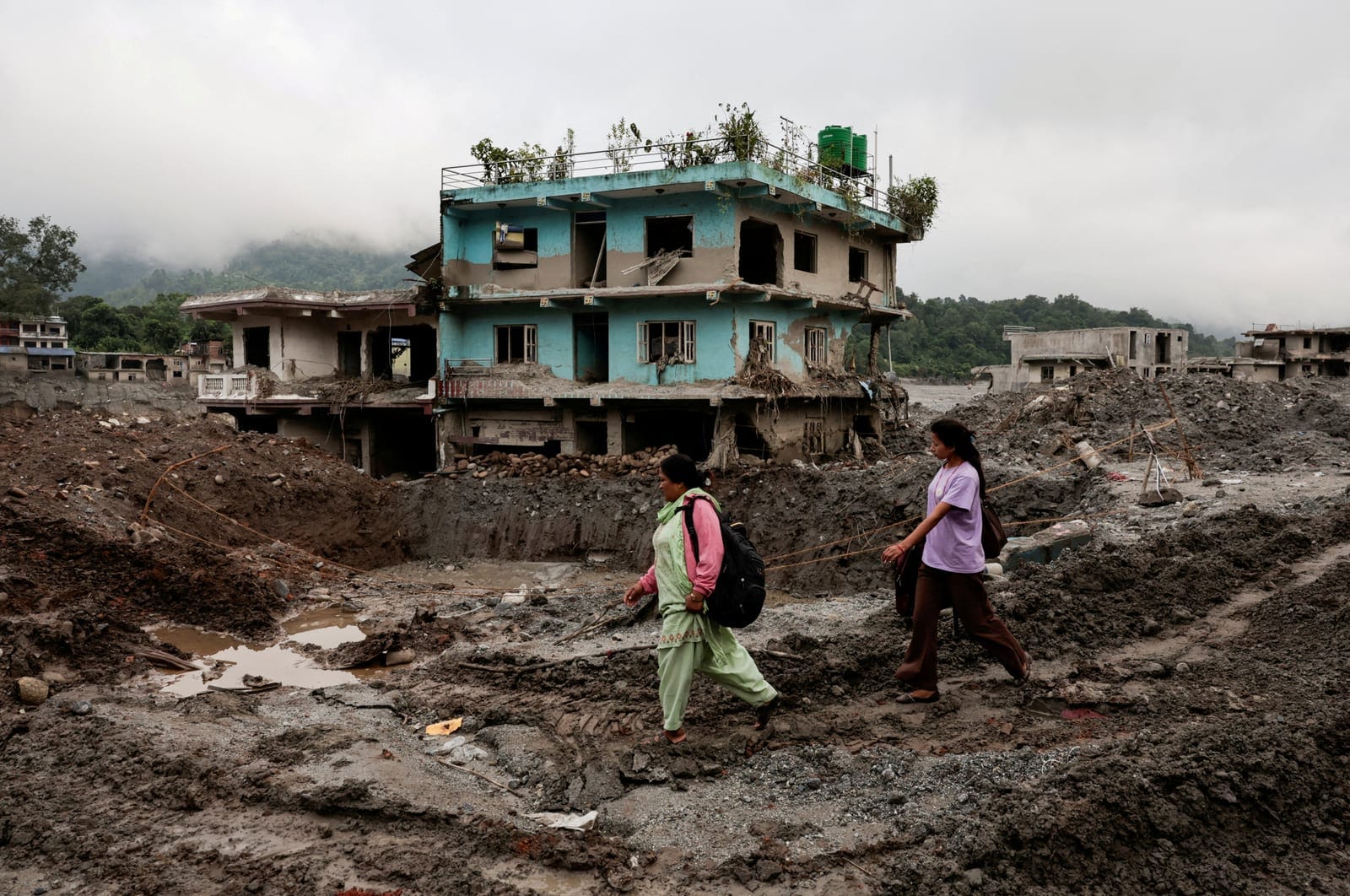 FILE PHOTO: People walk past damaged houses following deadly flash floods and a mudslide in Devighat, Nuwakot district, Nepal, September 21, 2026. REUTERS/Navesh Chitrakar/File Photo