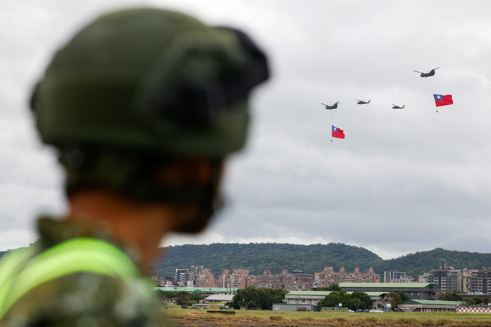 A member of Taiwan military watches as two US-made Chinook helicopters carry giant Taiwanese flags during a rehearsal ahead of Taiwan's National Day celebrations in Taipei, Taiwan, October 6, 2026. REUTERS/Ann Wang