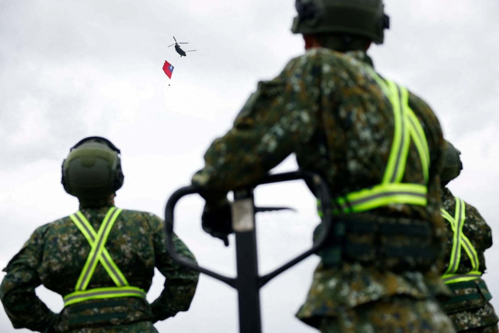 Taiwan military personnel watch as a US-made Chinook helicopter carries a giant Taiwanese flag during a rehearsal ahead of Taiwan's National Day celebrations in Taipei, Taiwan, October 6, 2026. REUTERS/Ann Wang