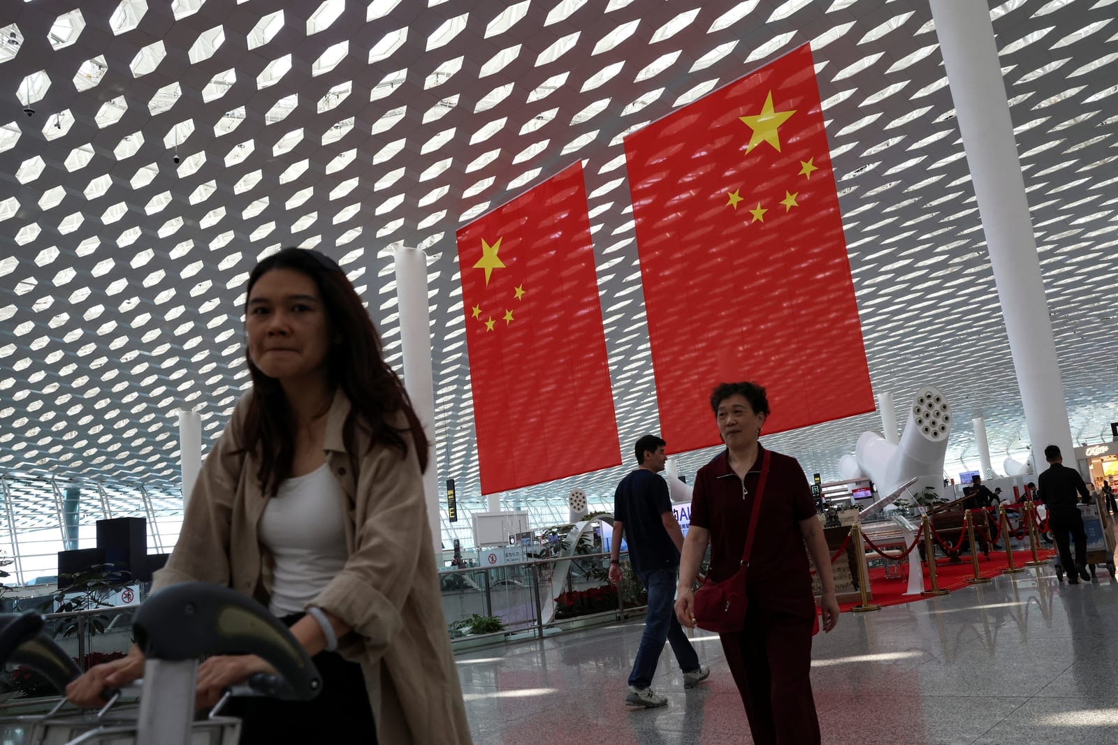 People walk past giant Chinese national flags hung at the Shenzhen Bao'an International Airport, ahead of the National Day holiday, in Shenzhen, Guangdong province, China September 28, 2026. REUTERS/Tingshu Wang