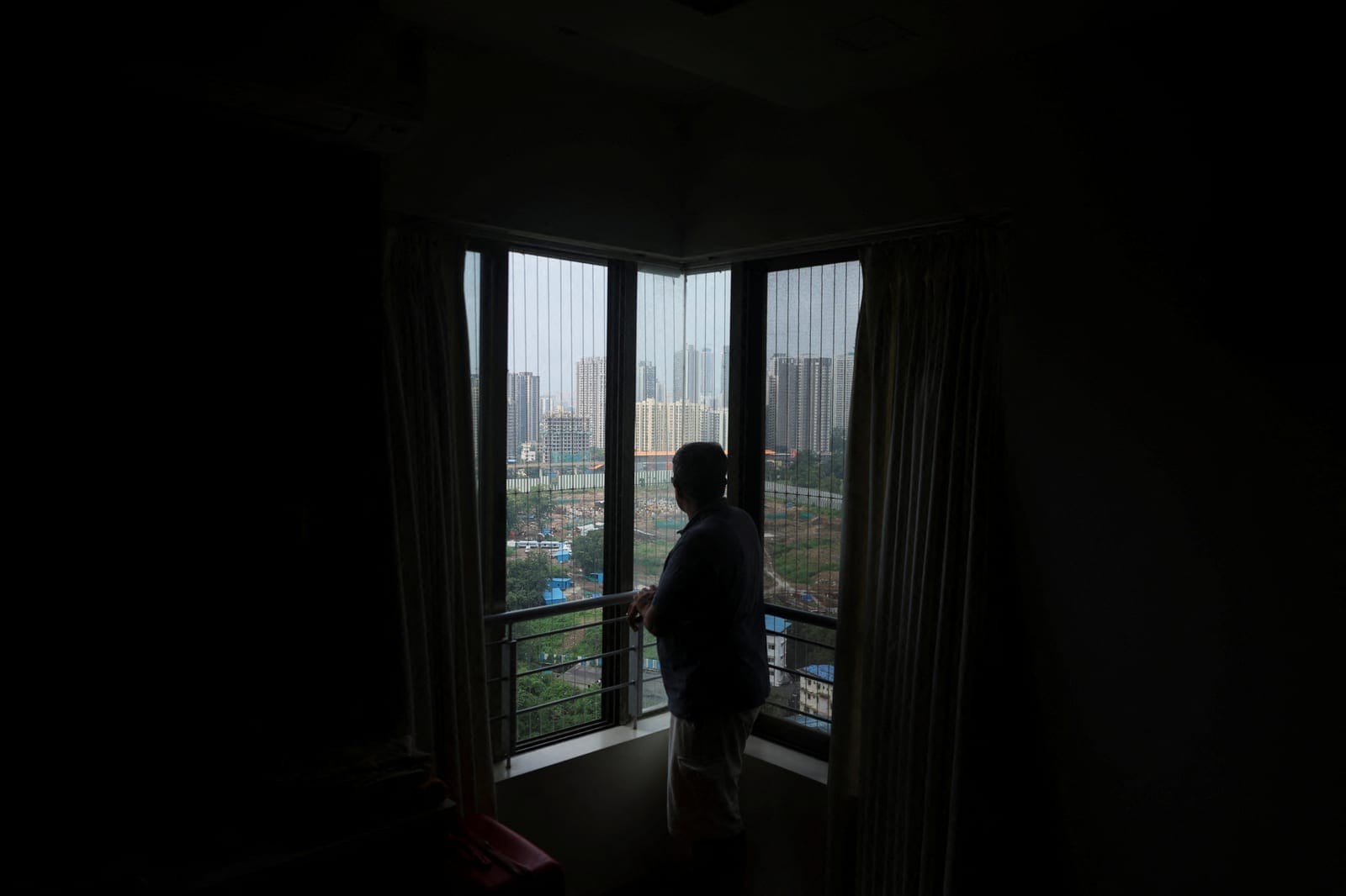 Tushar Shetty, a resident of the Lodha Luxuria residential complex, looks towards the site of an Amazon data centre from the the bedroom of his home in Thane, India, September 22, 2026. REUTERS/Francis Mascarenhas