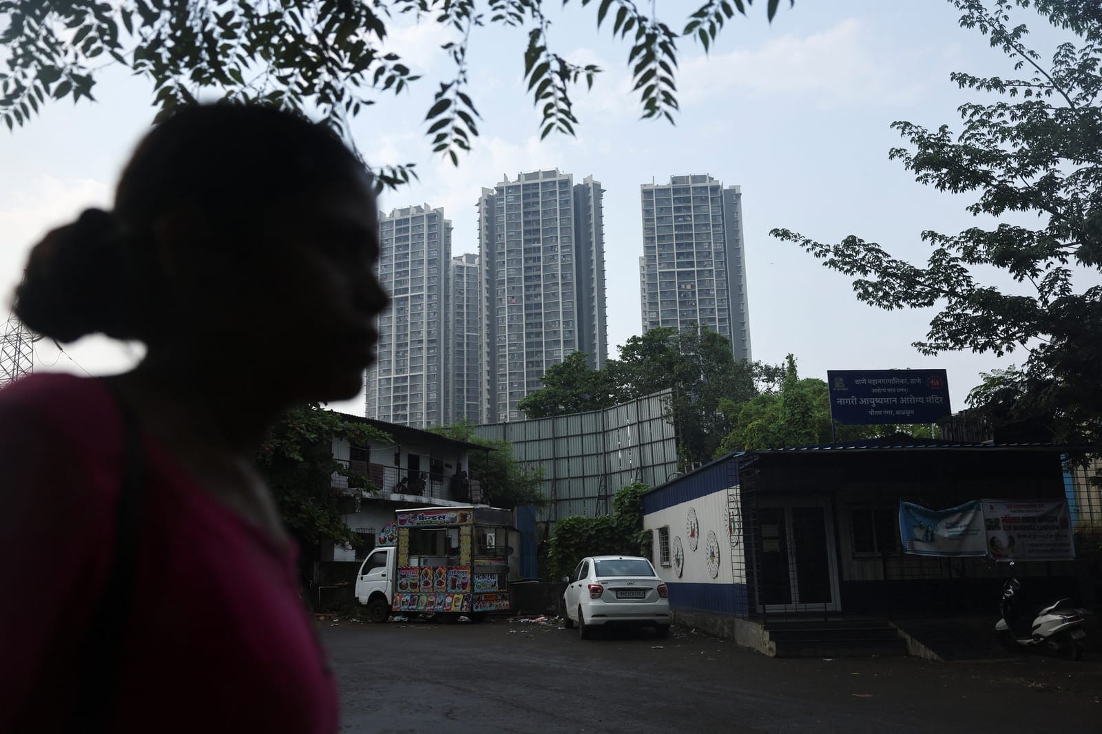 A woman walks past residential buildings near barricades marking the boundary of the site of an Amazon data centre in Thane, India, September 30, 2026. REUTERS/Francis Mascarenhas