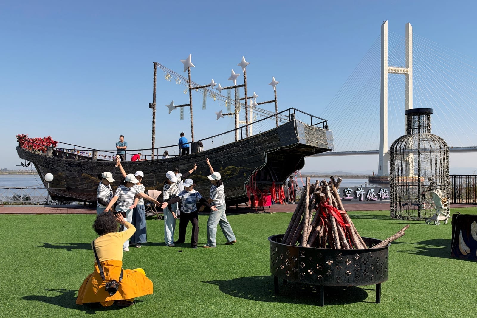 Tourists pose for photos by a boat-shaped installation near the New Yalu River Bridge, which is designed to link North Korea's Sinuiju with China's Dandong New Zone, in Dandong, Liaoning province, China October 6, 2026. REUTERS/Mandy Leong