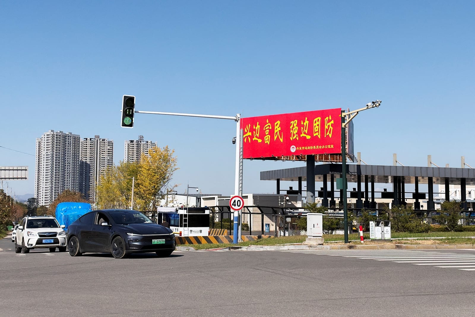 Vehicles travel past the Chinese customs facility for the New Yalu River Bridge, which is designed to link North Korea's Sinuiju with China's Dandong New Zone, in Dandong, Liaoning province, China October 6, 2026. The billboard reads, "Revitalise bor