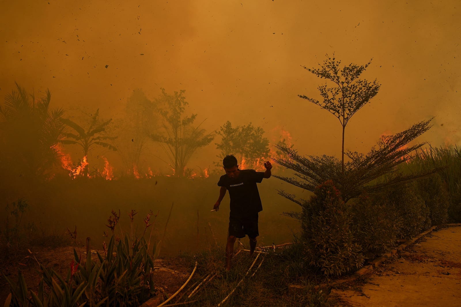 A resident walks as a wildfire burns near a residential area in Banyuasin, South Sumatra province, Indonesia, October 7, 2026. REUTERS/Abriansyah Liberto