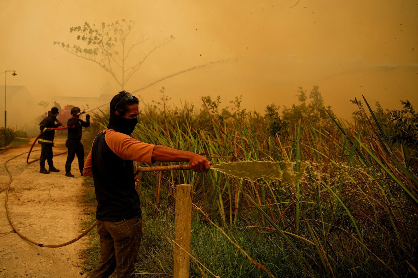 A resident sprays water to extinguish a wildfire near a residential area in Banyuasin, South Sumatra province, Indonesia, October 7, 2026. REUTERS/Abriansyah Liberto