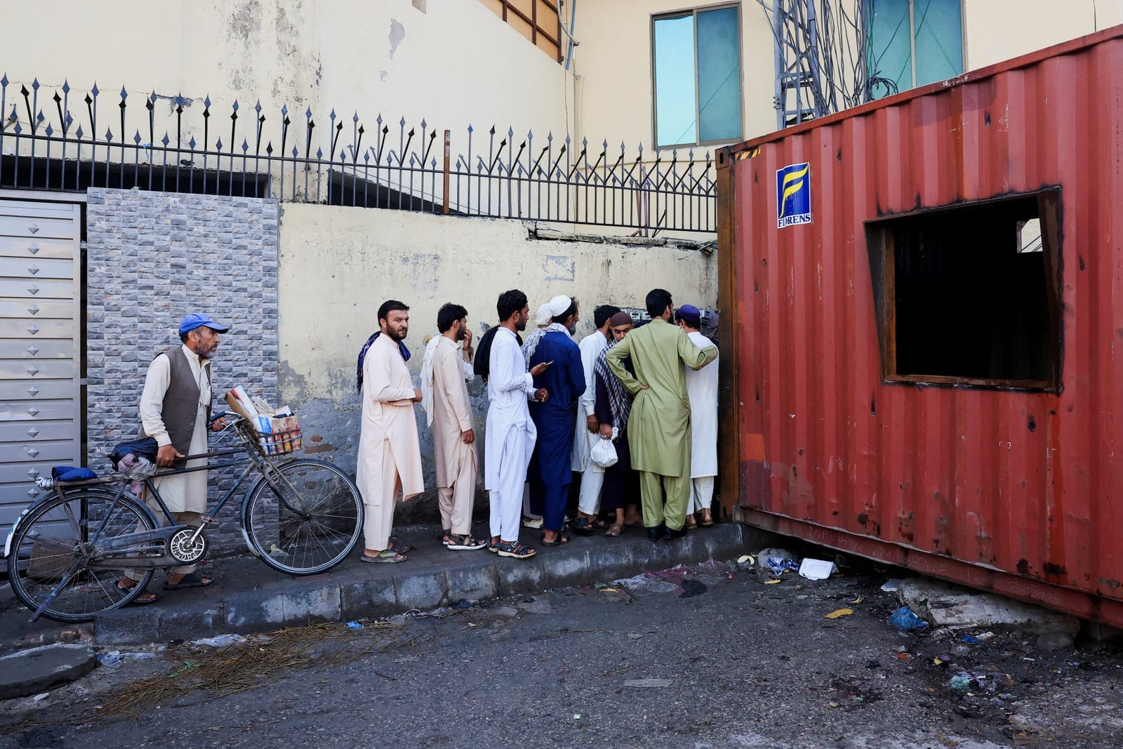 People cross shipping containers used to block access to the Red Zone, a day after Pakistan imposed a state of emergency in Khyber Pakhtunkhwa province, effectively suspending the provincial government run by jailed former Prime Minister Imran Khan's