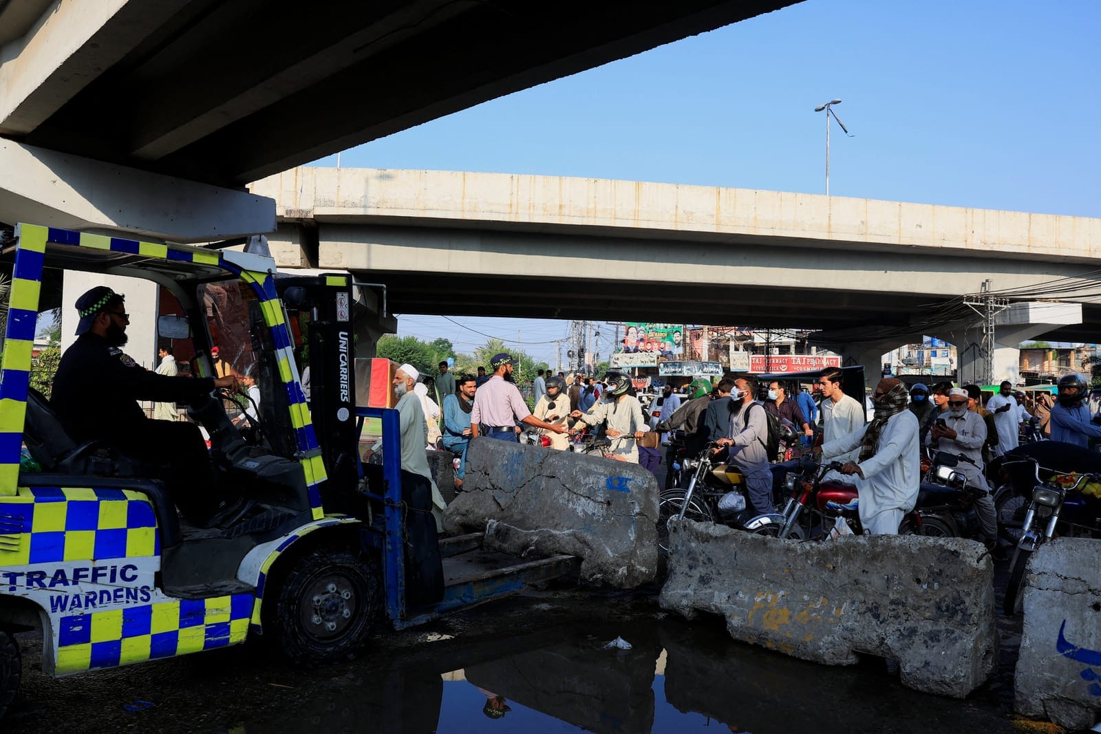 A traffic police officer puts cement blocks used to block access to the Red Zone, day after Pakistan imposed a state of emergency in Khyber Pakhtunkhwa province, effectively suspending the provincial government run by jailed former Prime Minister Imr
