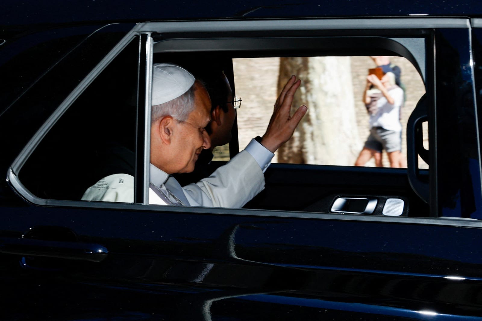 Pope Leo waves from a car window as he leaves the Vatican, ahead of his hospitalization for surgery to remove a lung nodule, in Rome, Italy, October 13, 2026. REUTERS/Remo Casilli