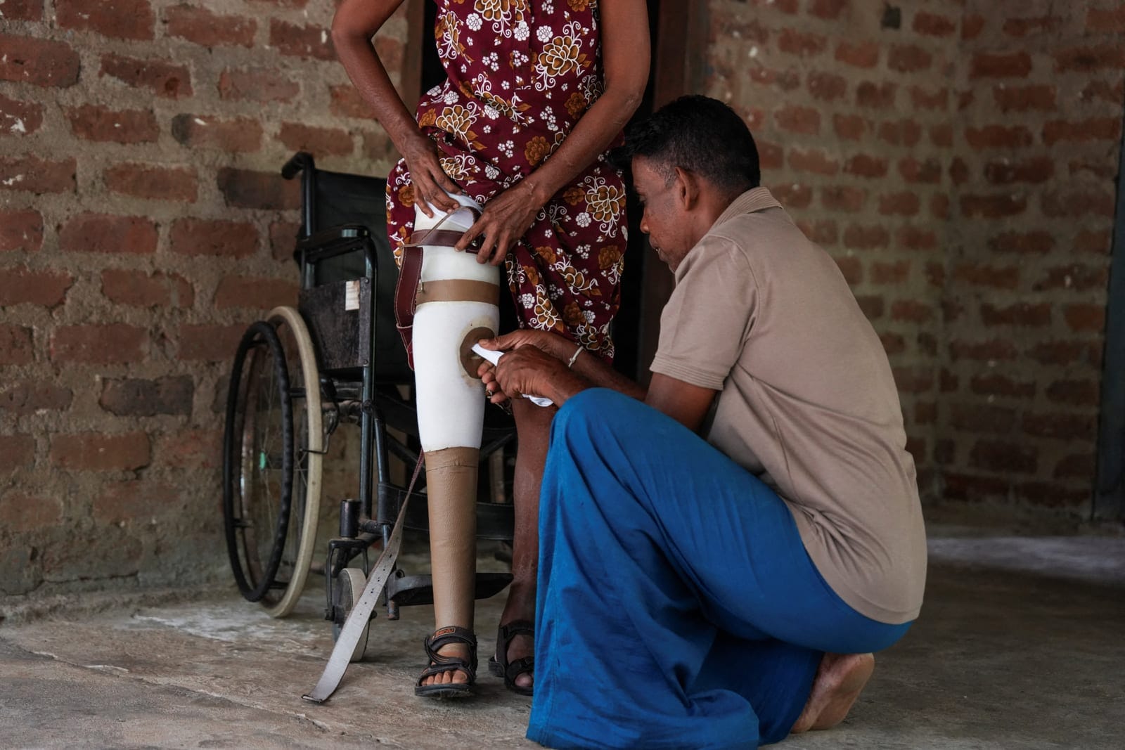 Wildlife officer Dewagiri Mudiyanselage Thilakaratne Bandara, 48, helps his wife, Rathnayake Mudiyanselage Shirani Ratnayake, 48, put on her prosthetic right leg in Siyambalangamuwa, Sri Lanka, September 17, 2026. Last December, an elephant wandered