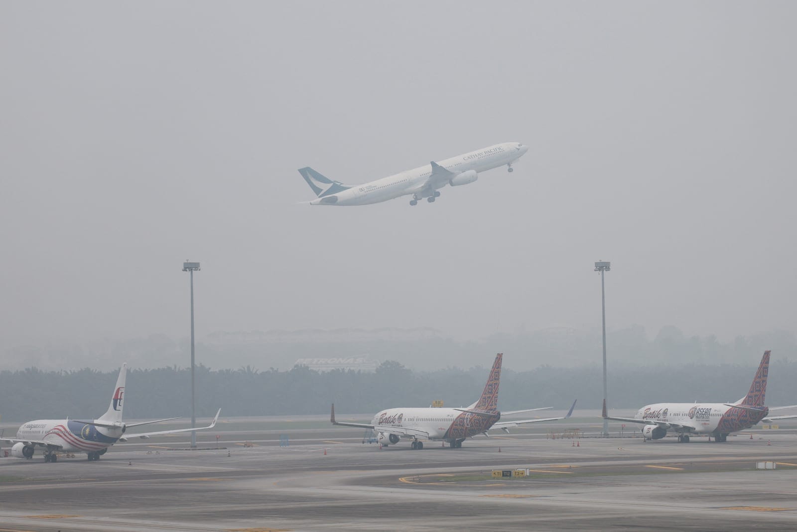 A Cathay Pacific aircraft takes off as aircraft from other airlines sit on the haze-shrouded tarmac at Kuala Lumpur International Airport in Sepang, Malaysia, October 14, 2026. REUTERS/Hasnoor Hussain