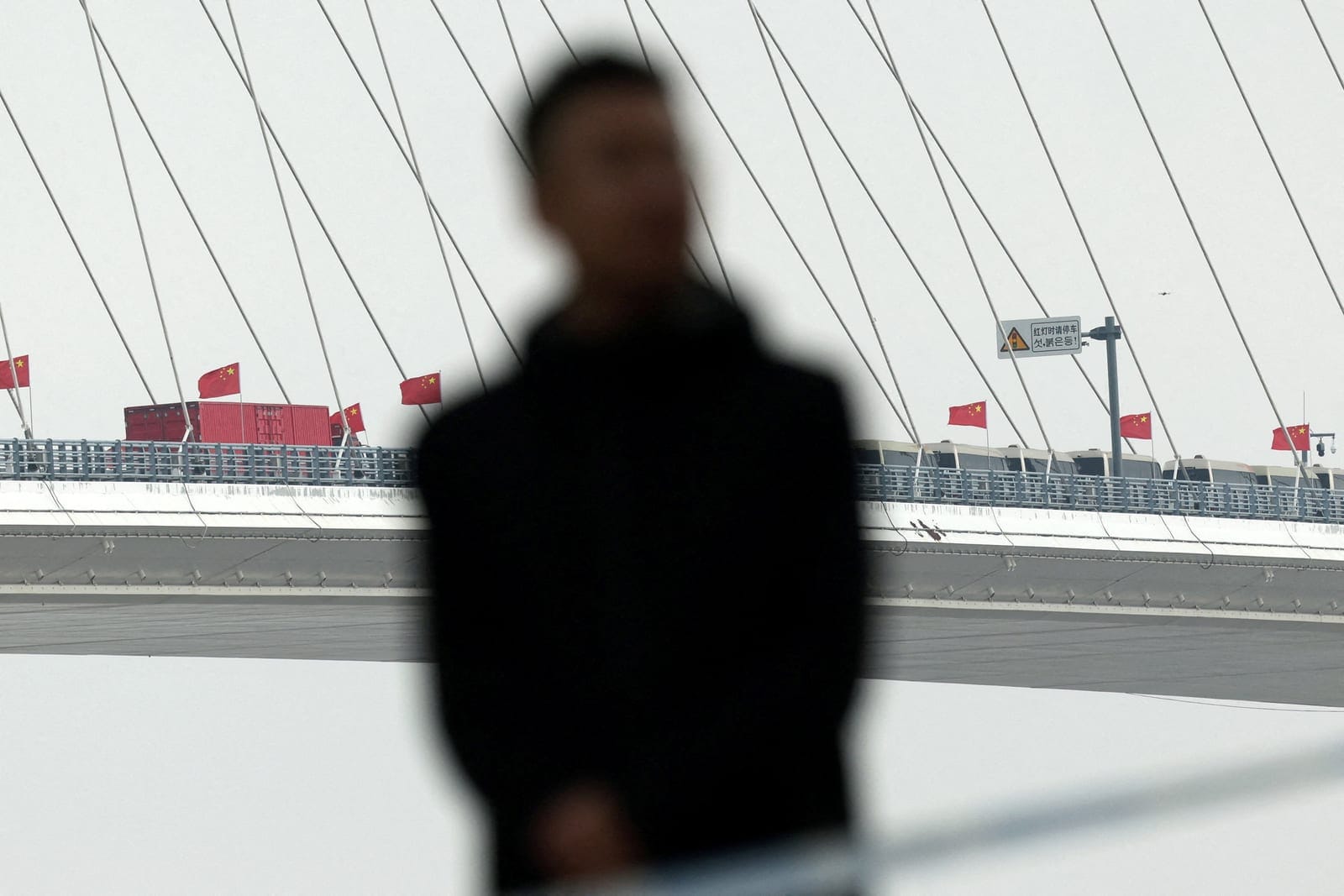 A security member keeps watch at a cordoned-off waterfront during the opening ceremony for the New Yalu River Bridge, which connects China’s Dandong New Zone and North Korea’s Sinuiju, in Dandong, Liaoning province, China, October 15, 2026. REUTERS/F