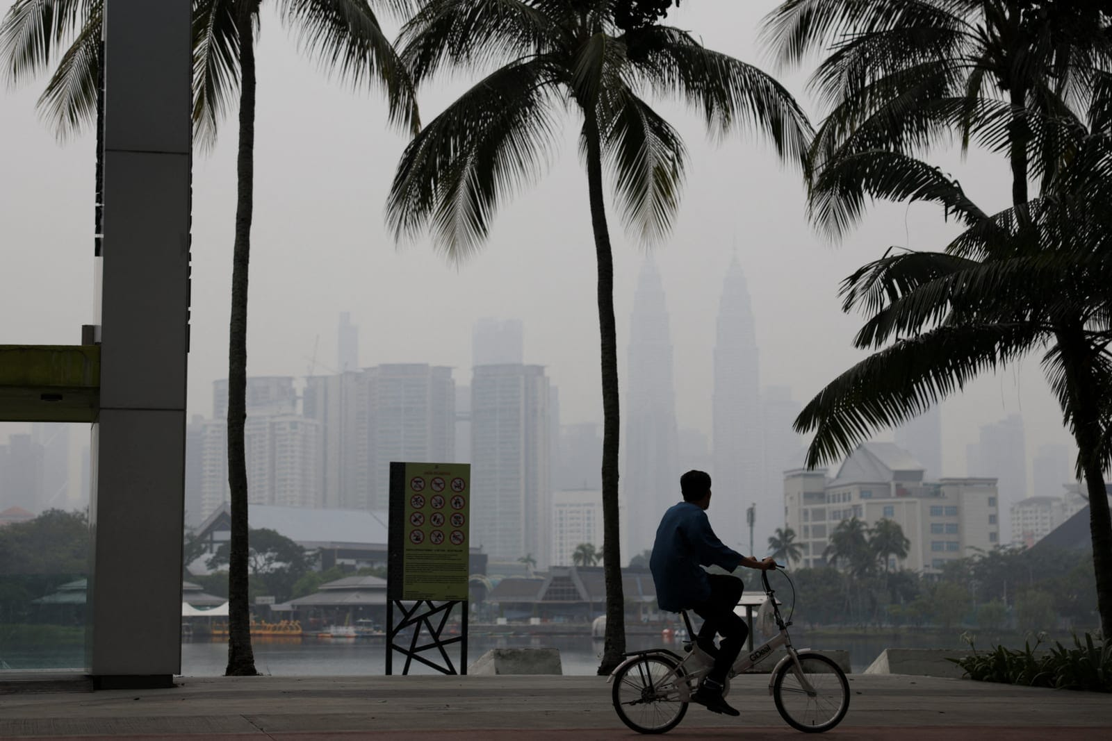 A man cycles with Kuala Lumpur’s skyline in the background shrouded in haze from regional wildfires, in Kuala Lumpur, Malaysia, October 15, 2026. REUTERS/Hasnoor Hussain