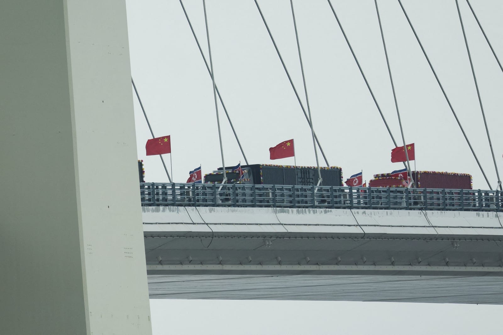 Trucks adorned with North Korean flags enter the Chinese side of the newly opened New Yalu River Bridge, which connects North Korea's Sinuiju with China's Dandong New Zone, in Dandong, Liaoning province, China October 15, 2026. REUTERS/Florence Lo