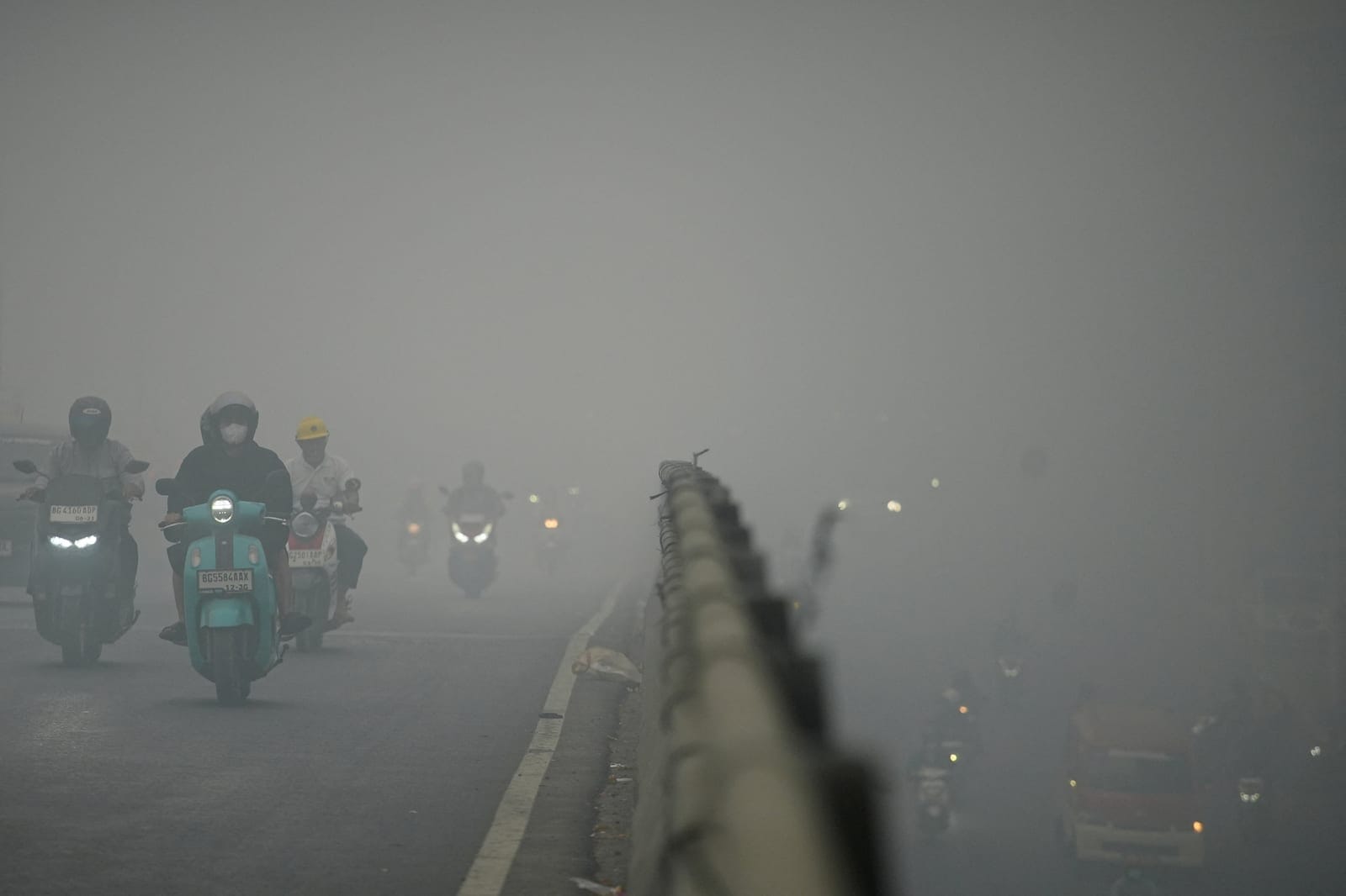 Motorists wearing protective masks ride on a bridge as haze from wildfires shrouds the area in Palembang, South Sumatra province, Indonesia, October 15, 2026. REUTERS/Abriansyah Liberto
