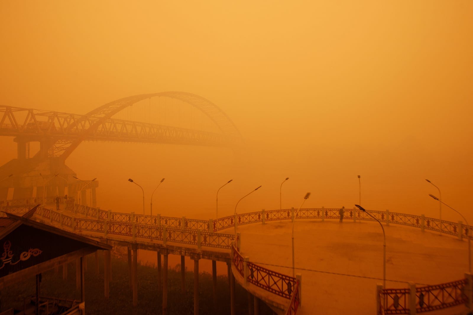 A person stands on a promenade as haze from wildfires shrouds the area, on the bank of the Kahayan River in Palangka Raya, Central Kalimantan province, Indonesia, October 14, 2026. REUTERS/Arief Rahman Septian Prathama