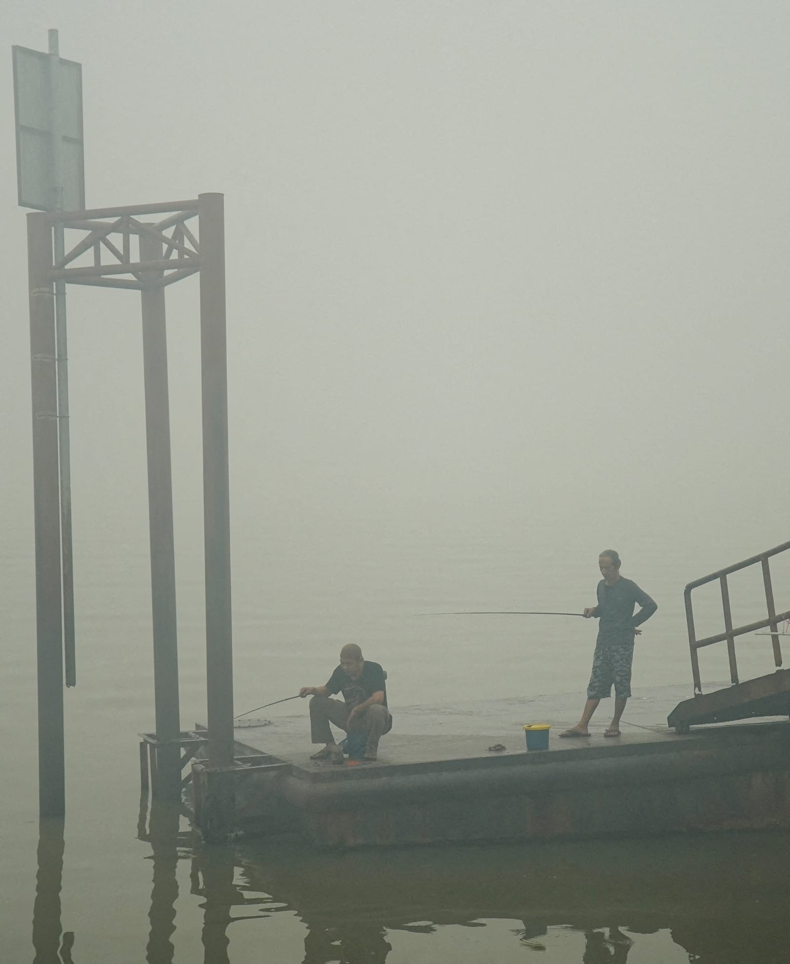 People fish on the Musi River as haze from wildfires shrouds the area in Palembang, South Sumatra province, Indonesia, October 15, 2026. REUTERS/Abriansyah Liberto