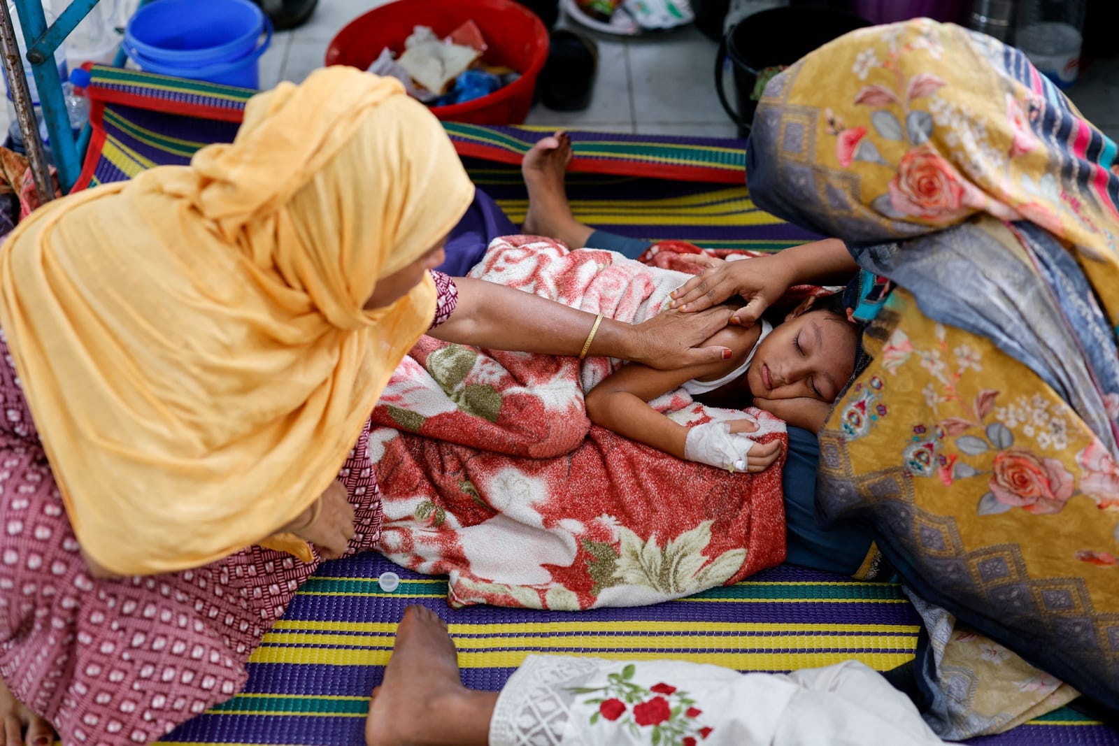 Relatives comfort six-year-old Istiyak Mahmud Zayan, who is receiving treatment on the floor of the overcrowded measles isolation ward of Shahid Shamsuddin Ahmed Hospital after developing symptoms of measles, in Sylhet, Bangladesh, September 12, 2026