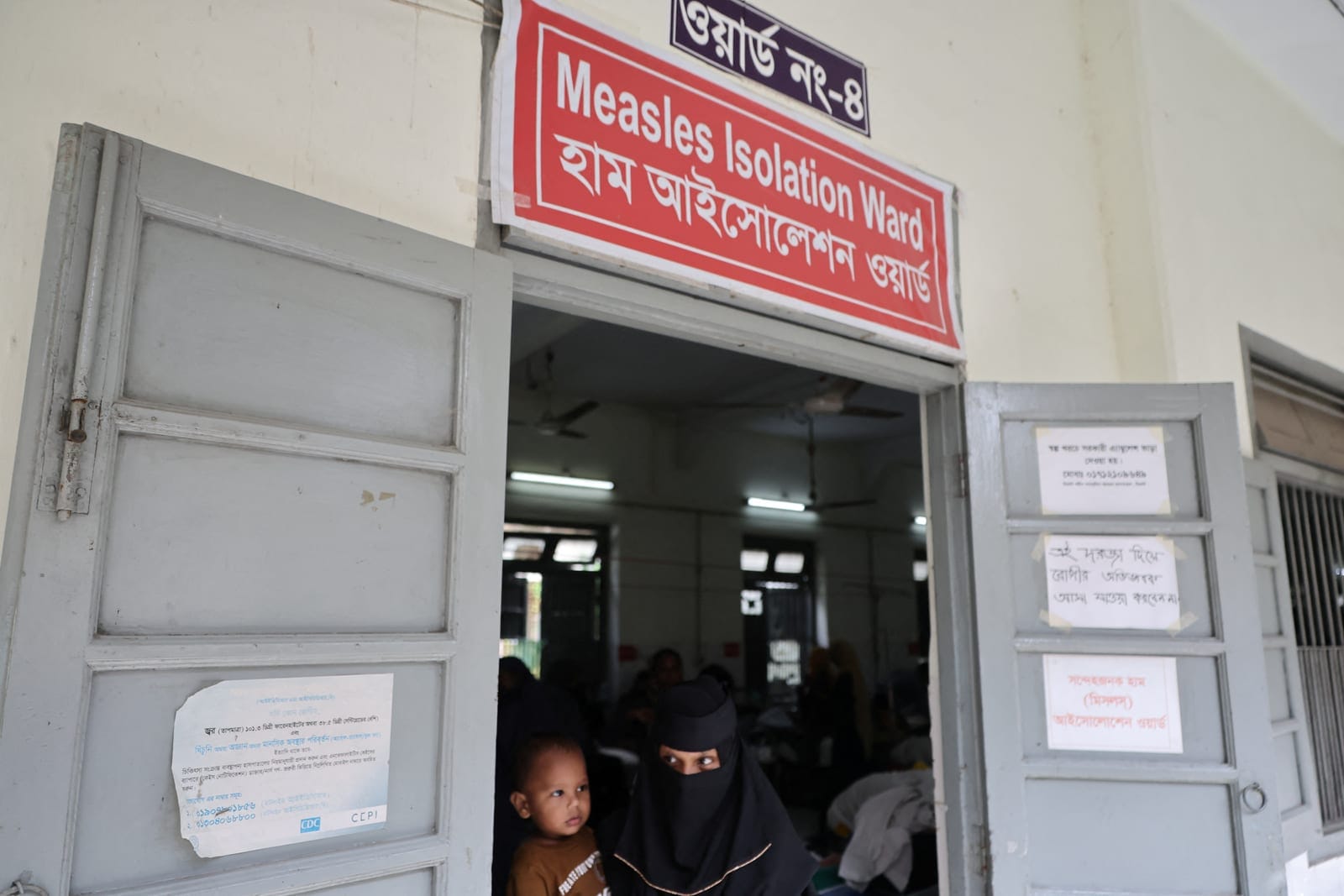 A woman carries a child as she leaves the measles isolation ward at Shahid Shamsuddin Ahmed Hospital in Sylhet, Bangladesh, September 12, 2026. REUTERS/Mohammad Ponir Hossain
