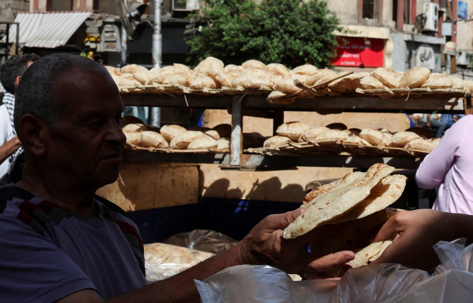 An Egyptian man holds traditional loaves of bread from a bakery, as disruptions to Black Sea grain exports and Red Sea shipping routes increase costs for wheat importers, in downtown Cairo, Egypt, October 13, 2026. REUTERS/Amr Abdallah Dalsh